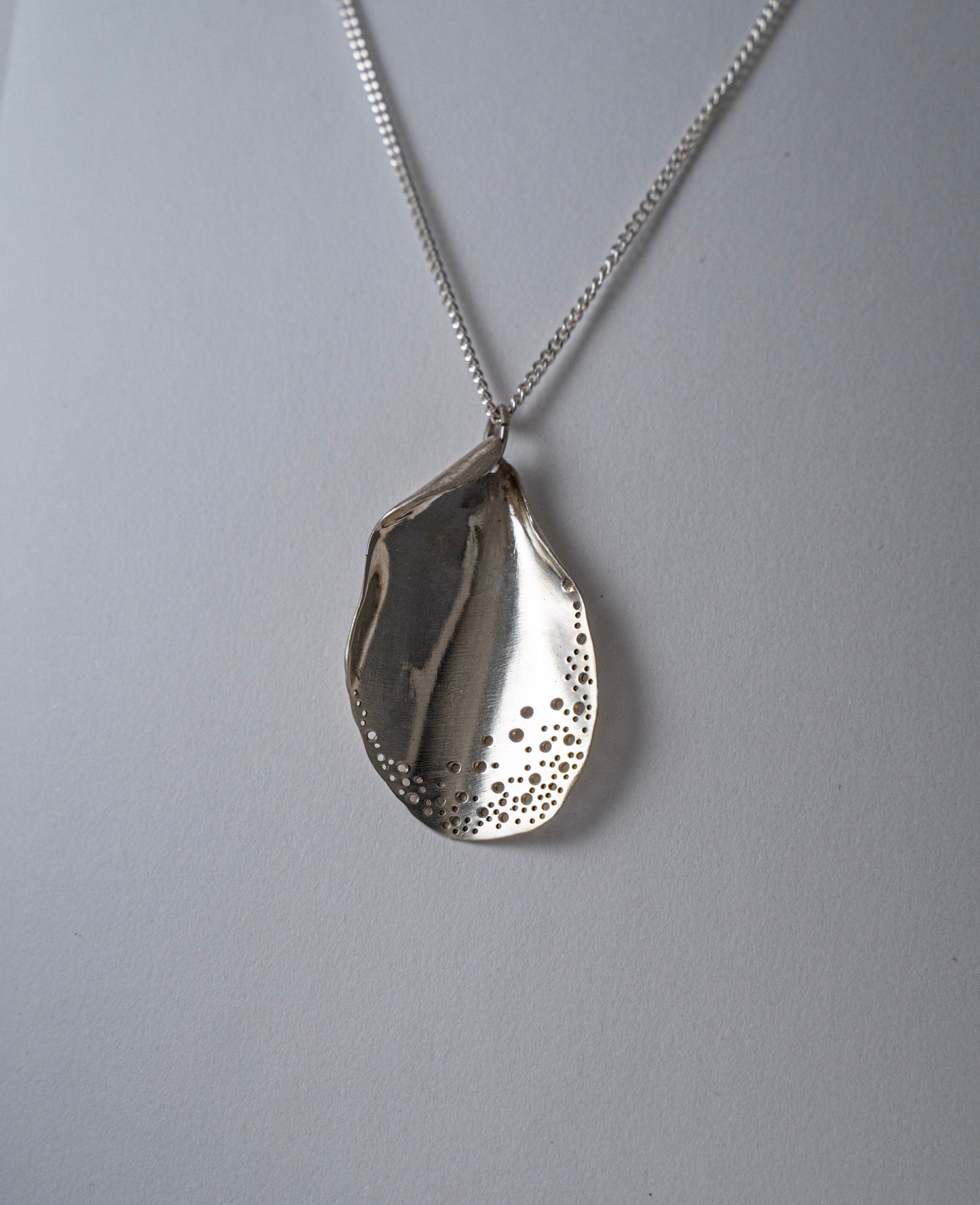 Silver teardrop pendant necklace on a gray background
