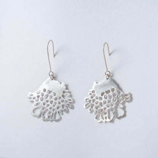 Pair of silver lace-style earrings on a light gray background