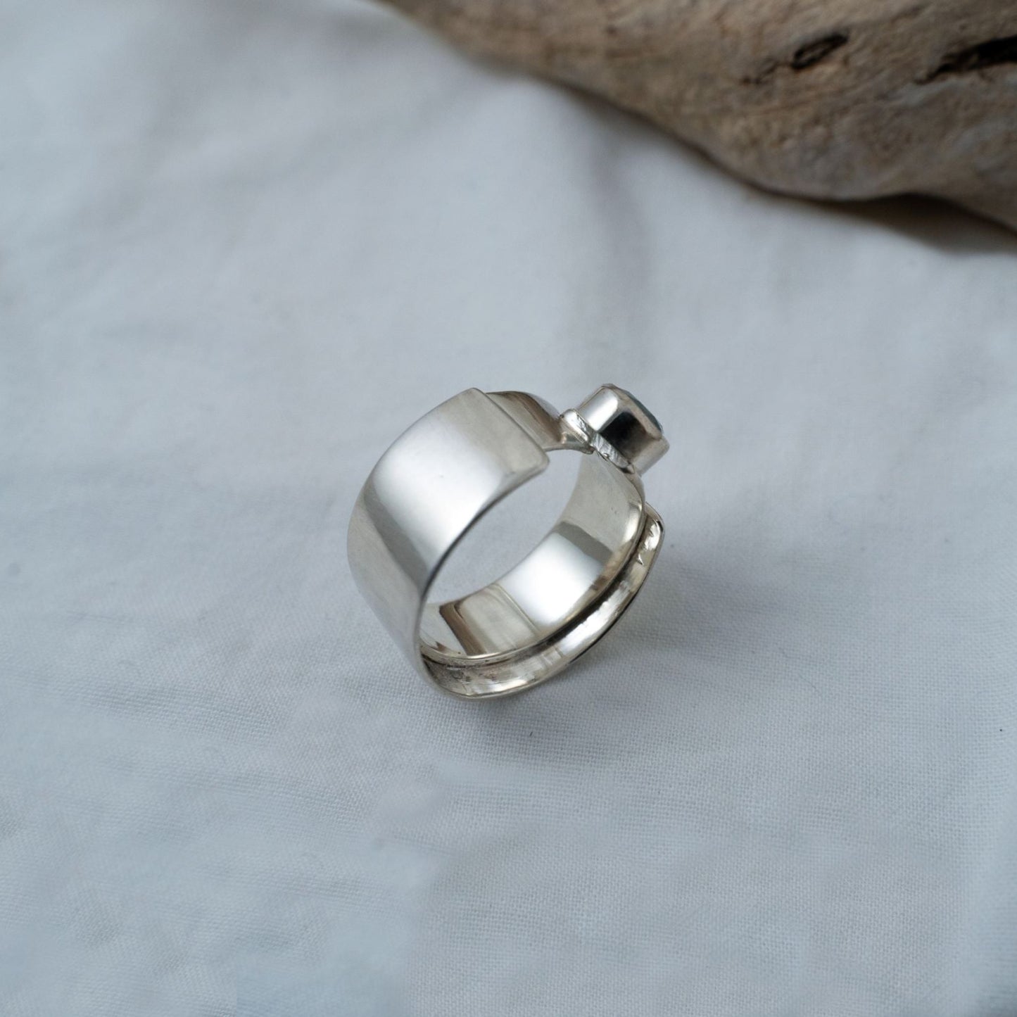 A closer look at the shank of the round cut, aquamarine, silver ring. It shows the double shank that will sit on one's finger with this ring. A rather thick, wide and chunky statement ring. A perfect item that transcends gender.