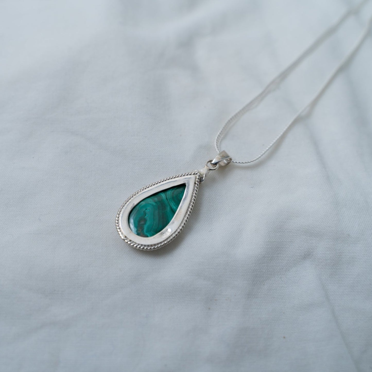 This is a photograph of the back of the malachite, silver pendant. It shows the craftsmanship of the entire pendant for both the front and back of the piece.