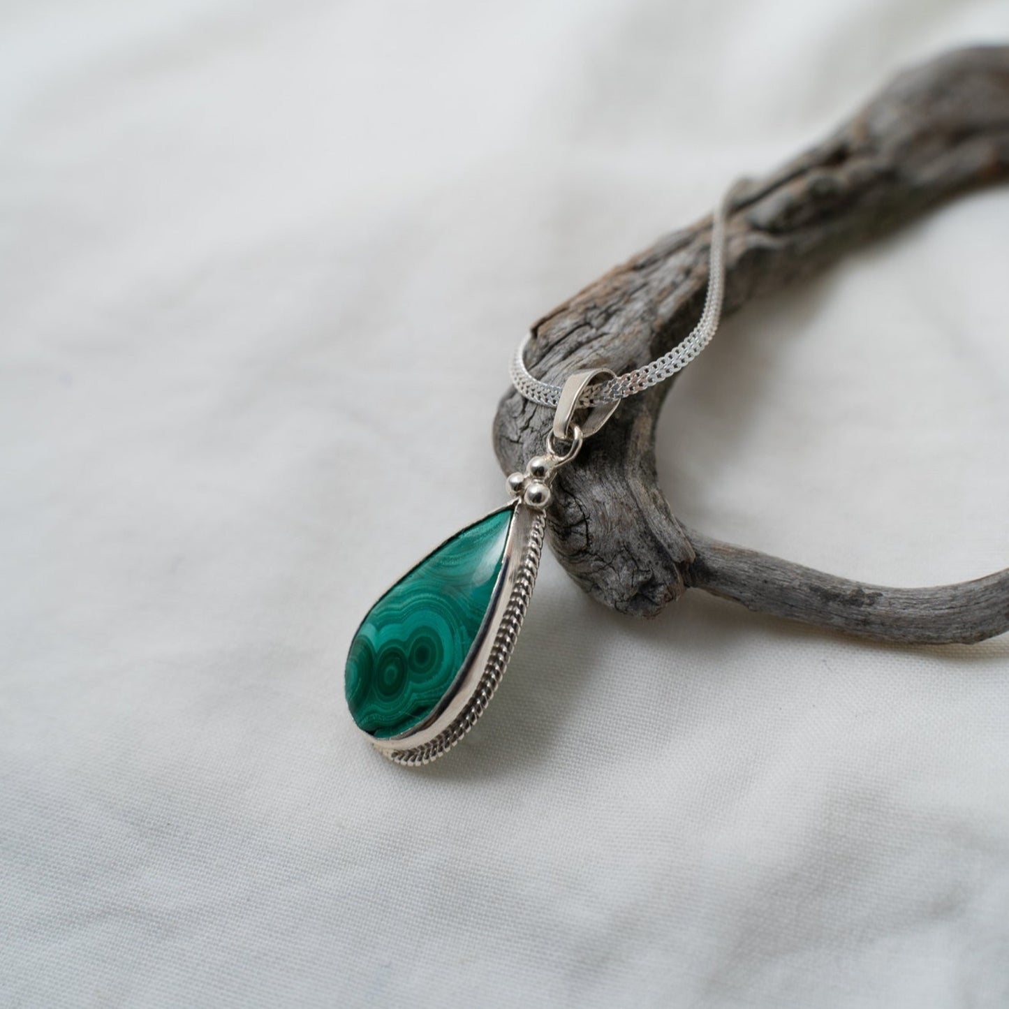 A closer look at the natural ringlet formations in the malachite gemstone and how they are designed to compliment the three triangular silver granules that sit at the top of the teardrop.