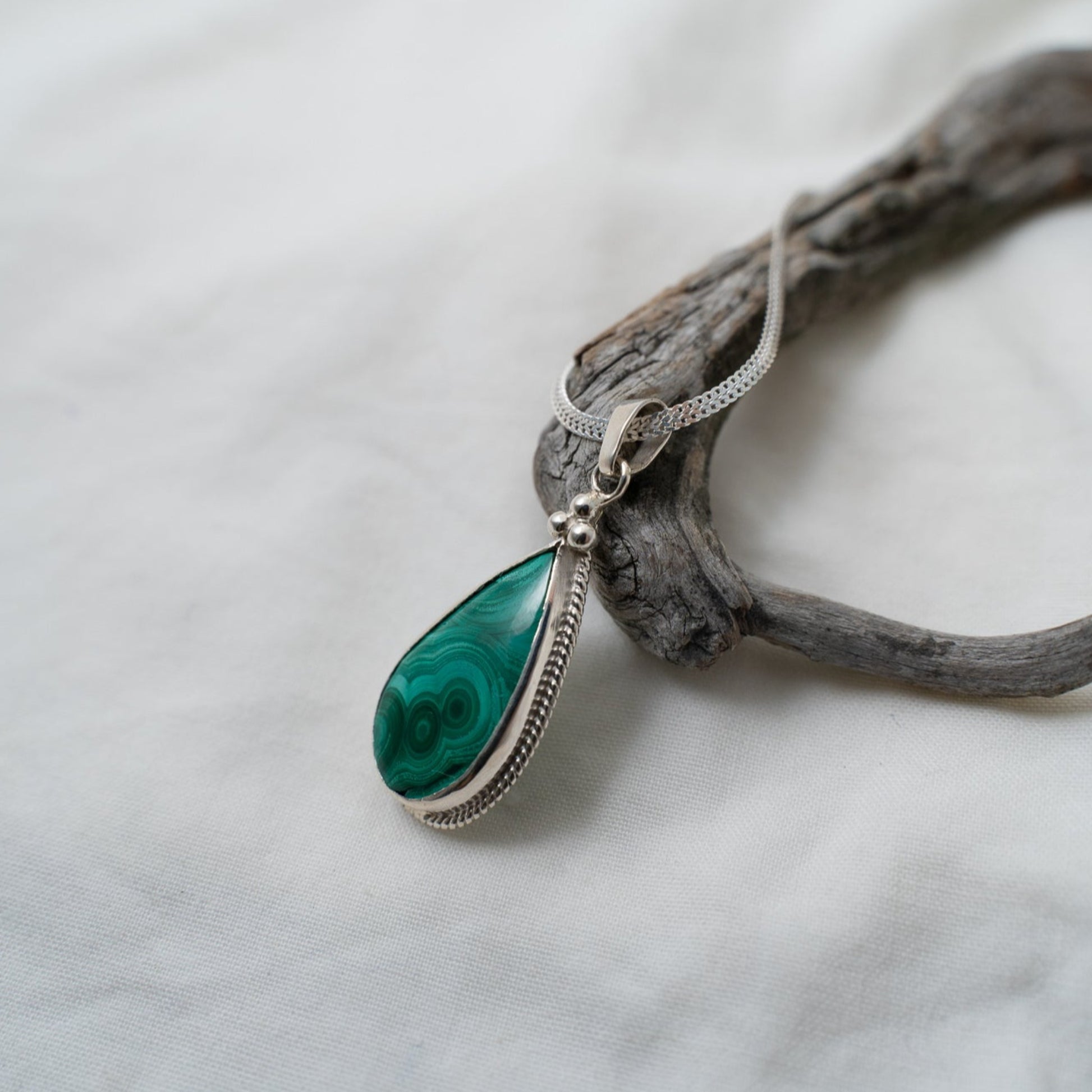 A closer look at the natural ringlet formations in the malachite gemstone and how they are designed to compliment the three triangular silver granules that sit at the top of the teardrop.