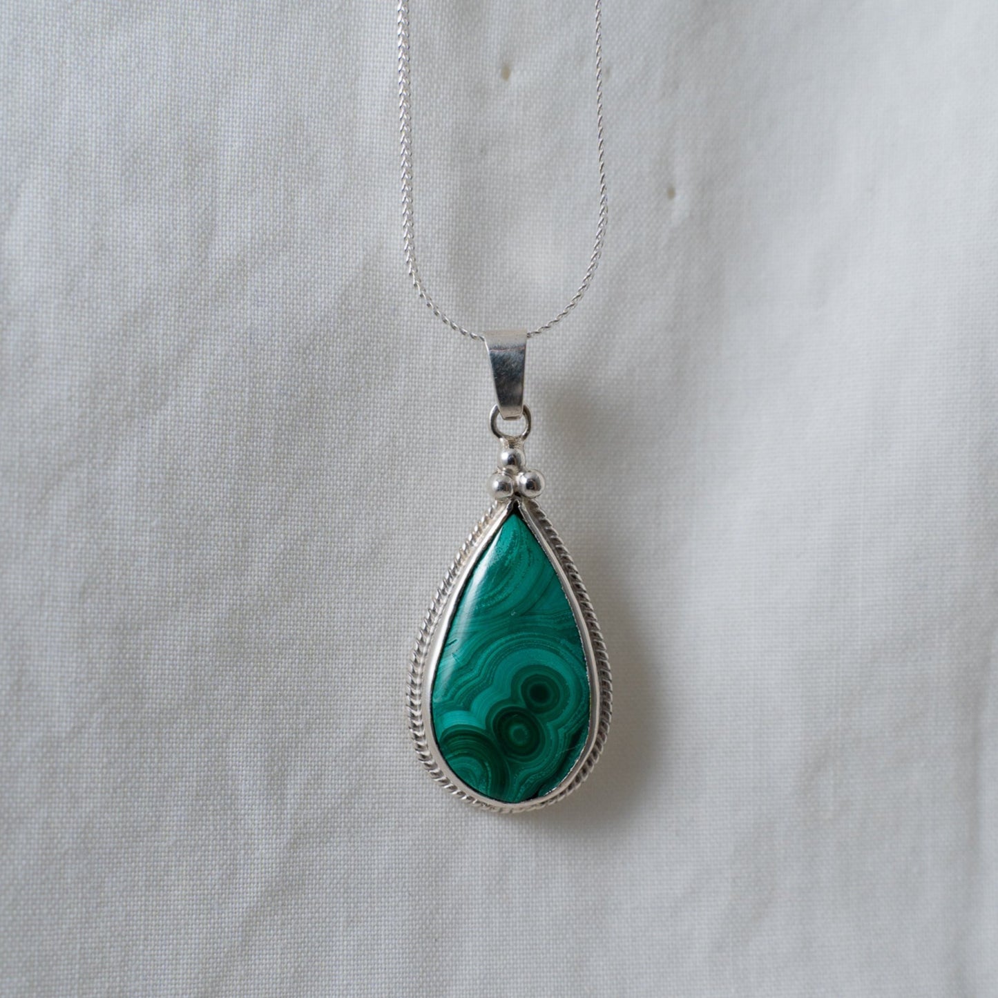 A head on shot of the teardrop malachite, silver pendant to depict how the pendant would look when worn.