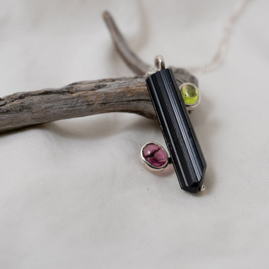 An up-close, side look at the black and pink tourmaline with peridot silver pendant.