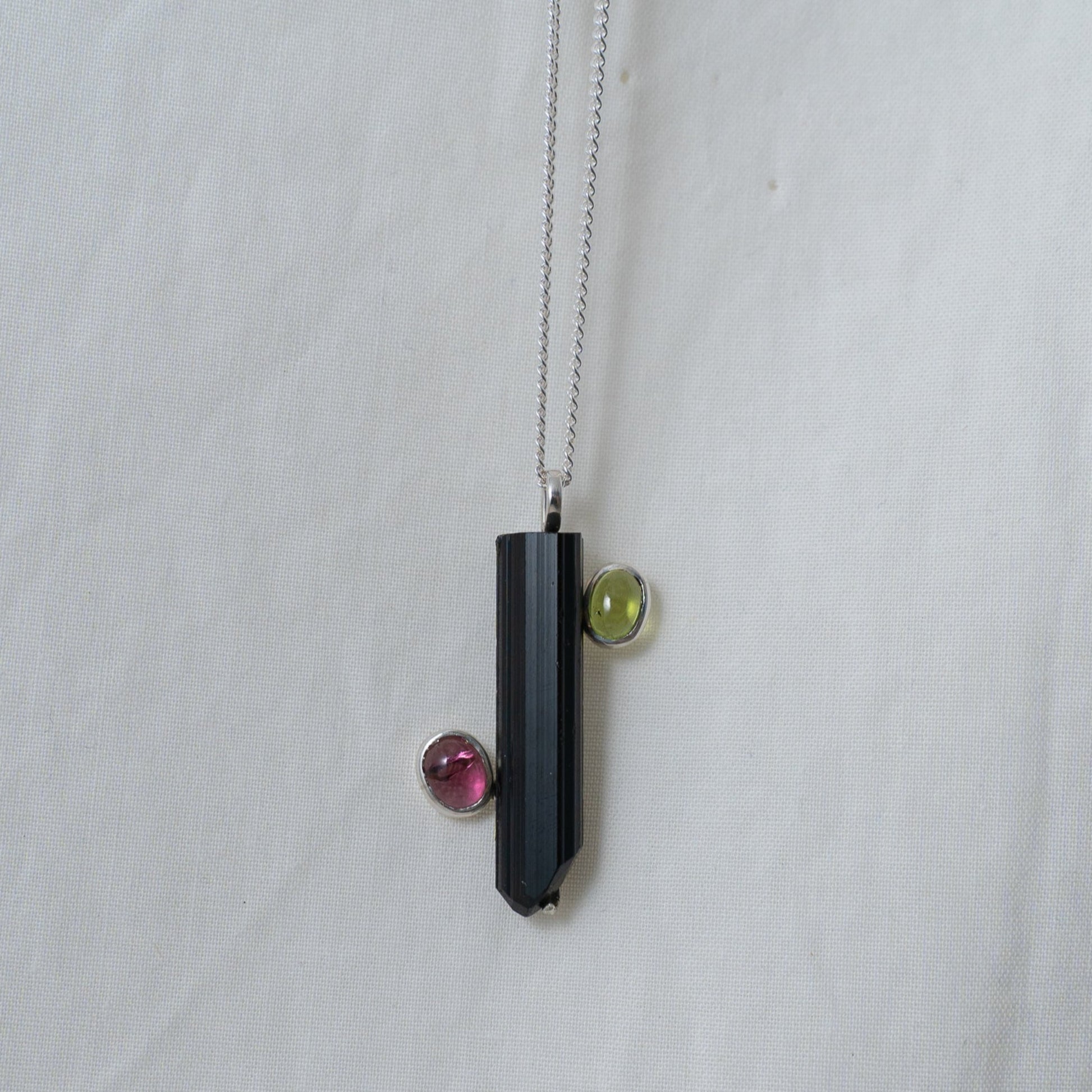 A head on photograph of the black and pink tourmaline with a green peridot silver pendant.. It shows you how it would look when worn.
