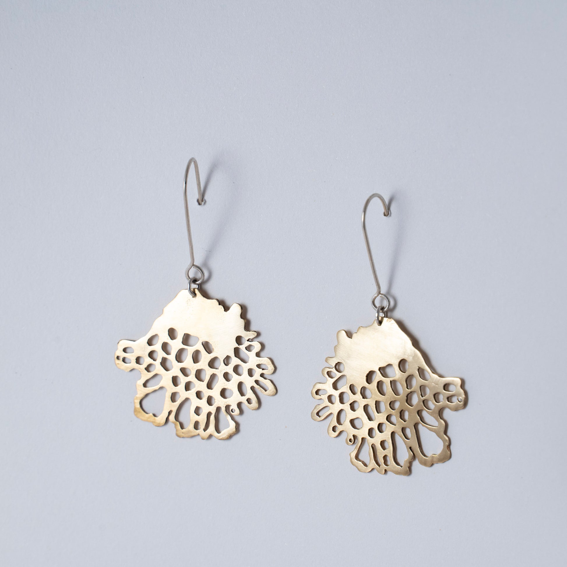 Pair of gold lace-style earrings on a light gray background