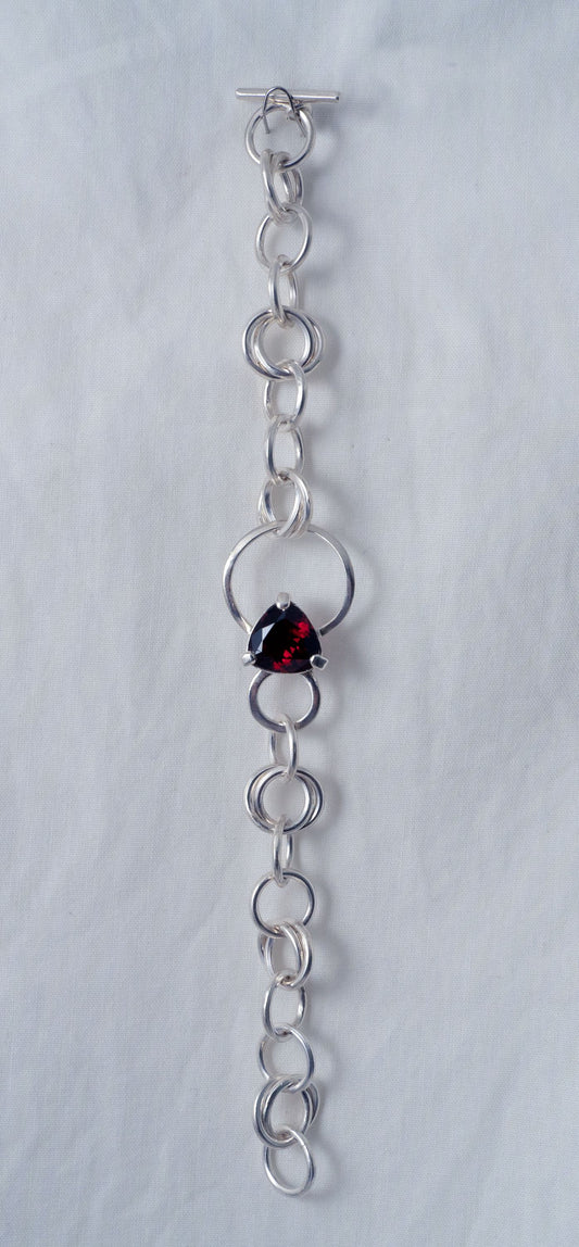 Handcrafted silver link bracelet with trilliant cut deep red garnet.