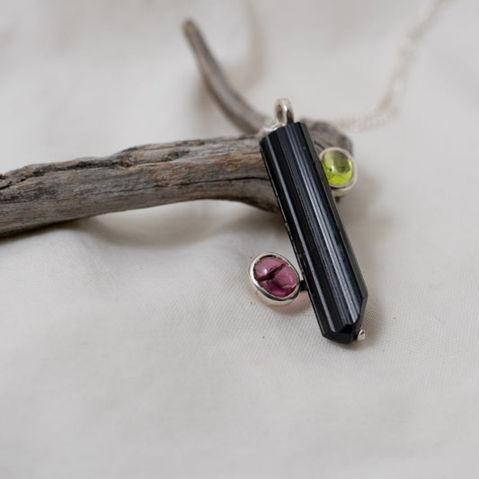 An up-close, side look at the black and pink tourmaline with peridot silver pendant. 